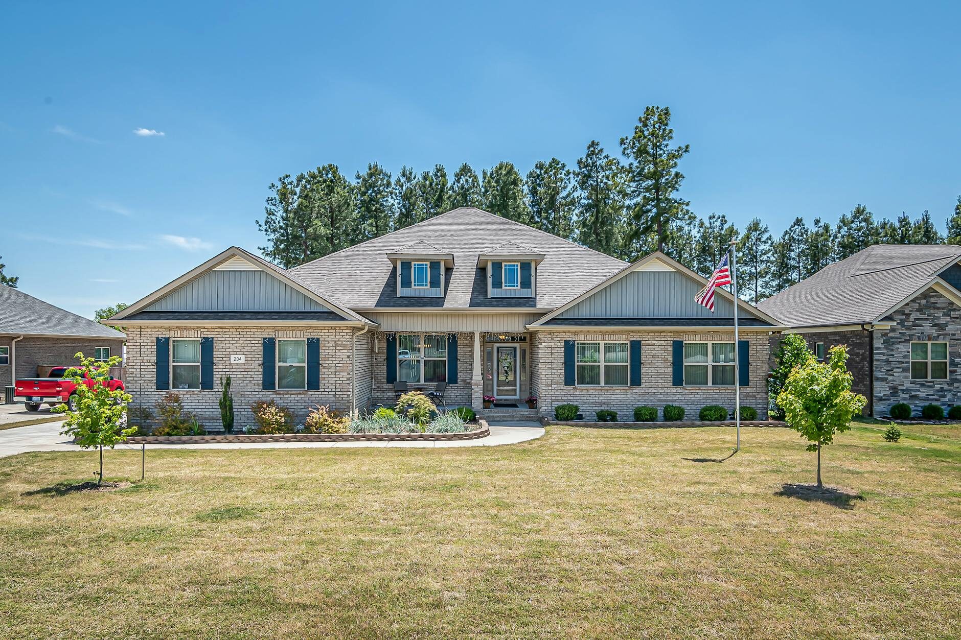 Brick ranch home with American flag and pine trees in a Southern suburban neighborhood