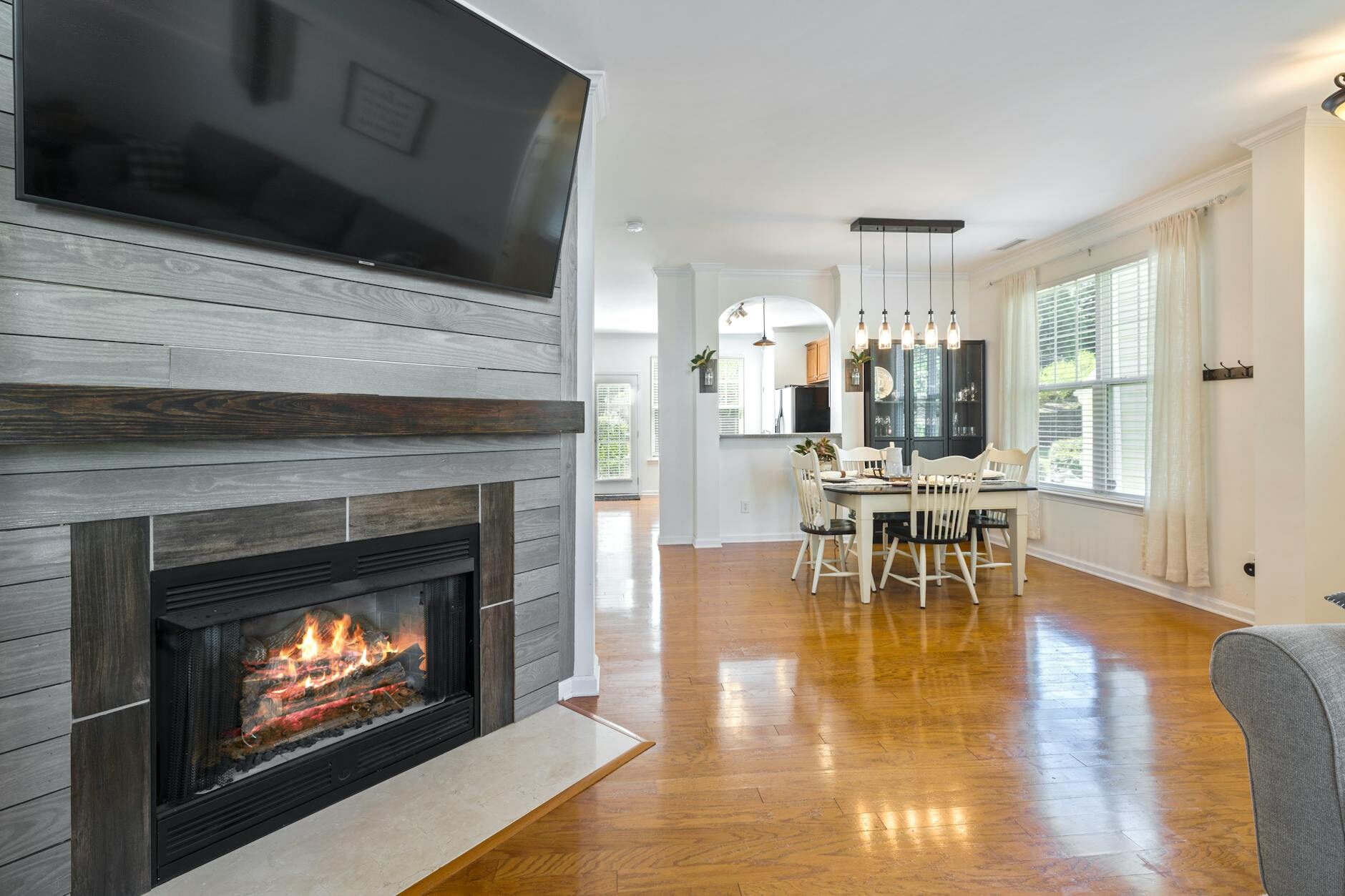 Open-plan living room with TV mounted above a wood plank fireplace accent wall